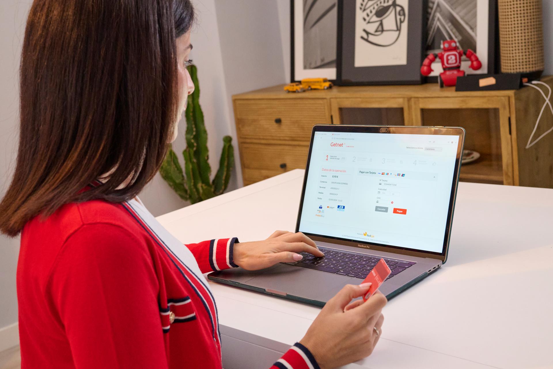 Mulher realizando compra com cartão de crédito santander em um computador portátil sobre uma mesa